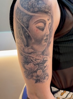 Tatuagem de Buda com flores no braço, por Alexandre Cunha.